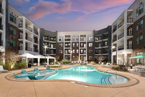 a swimming pool with lounge chairs in front of an apartment building